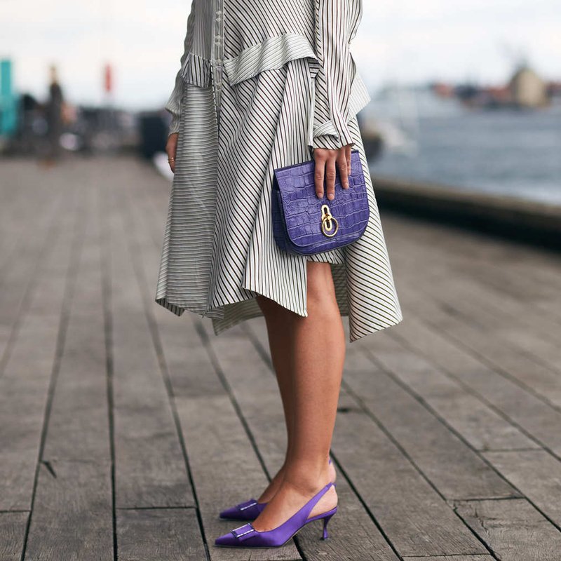 woman wearing a dress with purple kitten heel slingbacks and a purple bag
