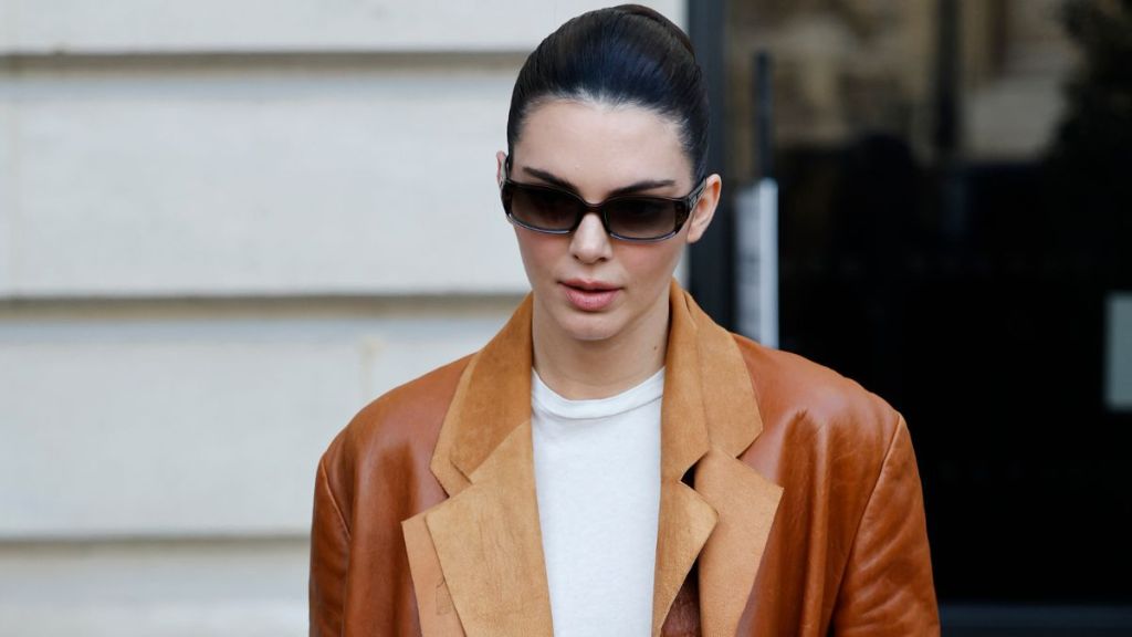 Kendall Jenner wears white top, brown leather double blazer, brown suede Hermès bag, black sunglasses, outside Schiaparelli, during Haute Couture Spring-Summer 2025 as part of Paris Fashion Week on January 27, 2025 in Paris, France.